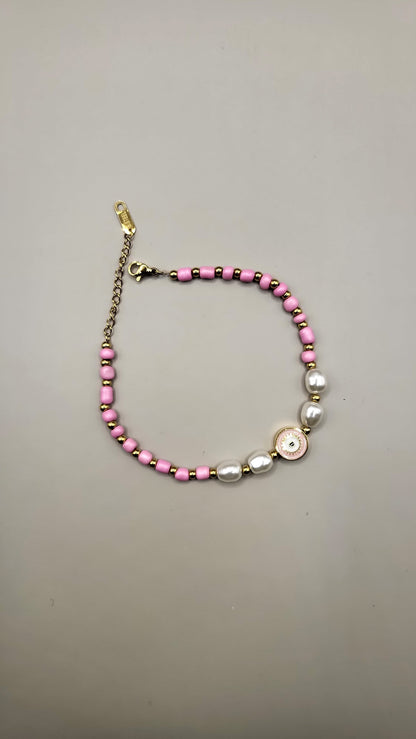Bracelet with pink beads and a gold clasp on a gray background