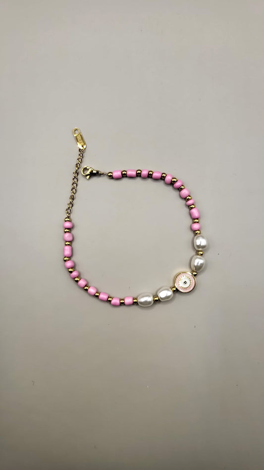 Bracelet with pink beads and a gold clasp on a gray background