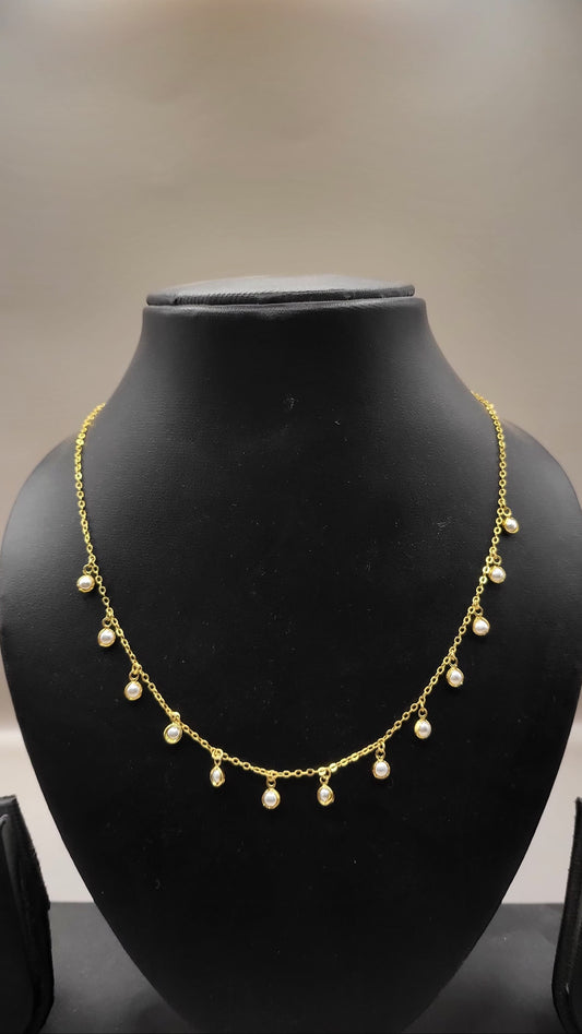 Gold necklace with pearls on a black mannequin bust against a neutral background